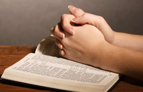 [Photo of an open Bible with folded hands on top]