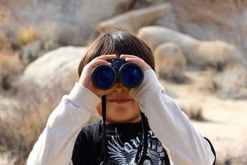 [Photo of a boy looking through a pair of binoculars]