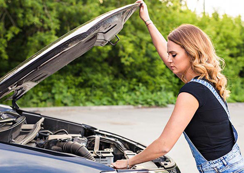 [Photo of a woman looking under the hood of a vehicle]