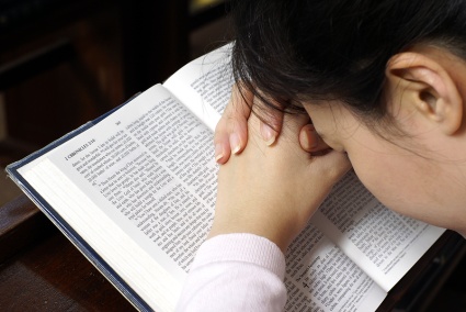 [Photo of a woman praying over her Bible]