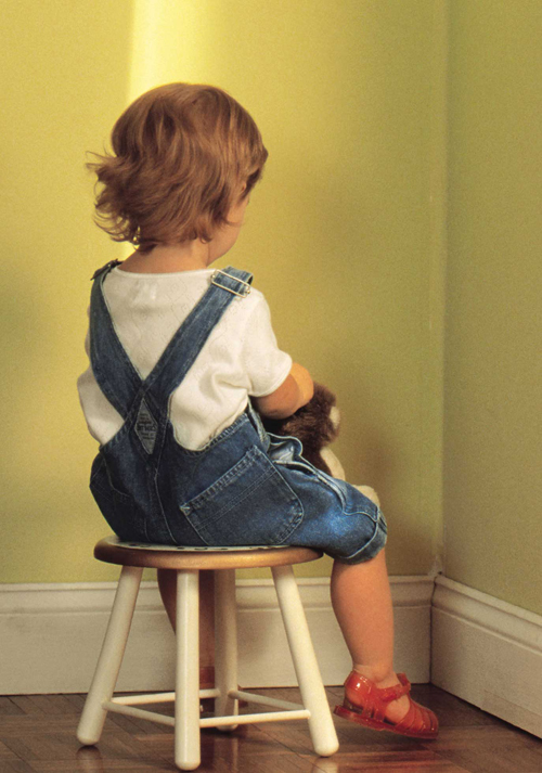 [Photo of a child sitting in a corner]