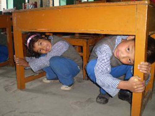 [Photo of children hiding under a table]