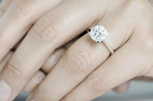 [Photo of an engagement ring on a woman's finger]