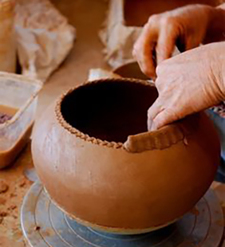 [Photo of a potter forming a pot]
