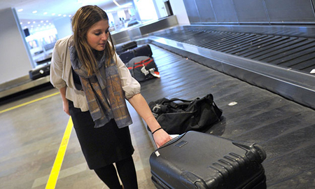 [Photo of a young woman getting her luggage at an airport]