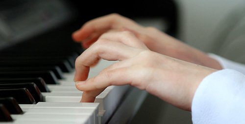 [Photo of a woman's hands on a piano keyboard]