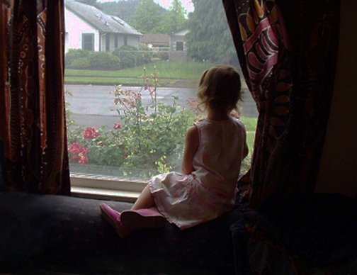 [Photo of a little girls looking out a window]