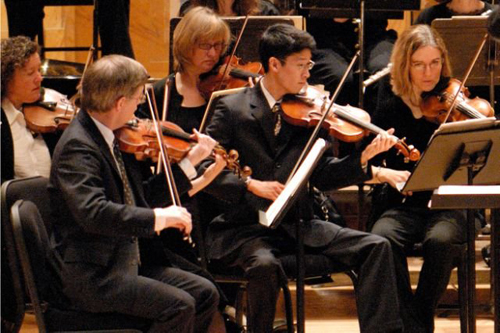 [Photo of a violin section of an orchestra]