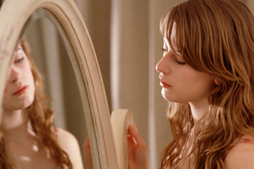 [Photo of a young woman looking into a mirror]