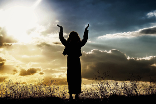 [Photo of a woman raising her arms in praise]