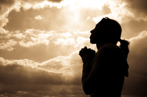 [Photo of a woman in silhouetter praying]